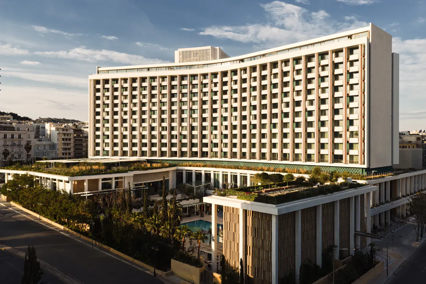 Εξωτερική όψη του Conrad Athens The Ilisian, με τη χαρακτηριστική πρόσοψη και την πισίνα.